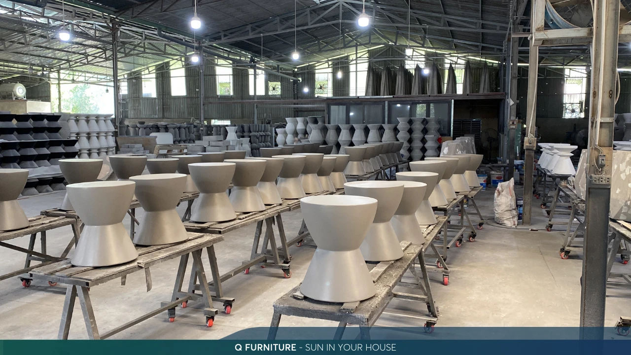 Rows of freshly cast concrete stools curing on steel racks inside the Q-Furniture factory