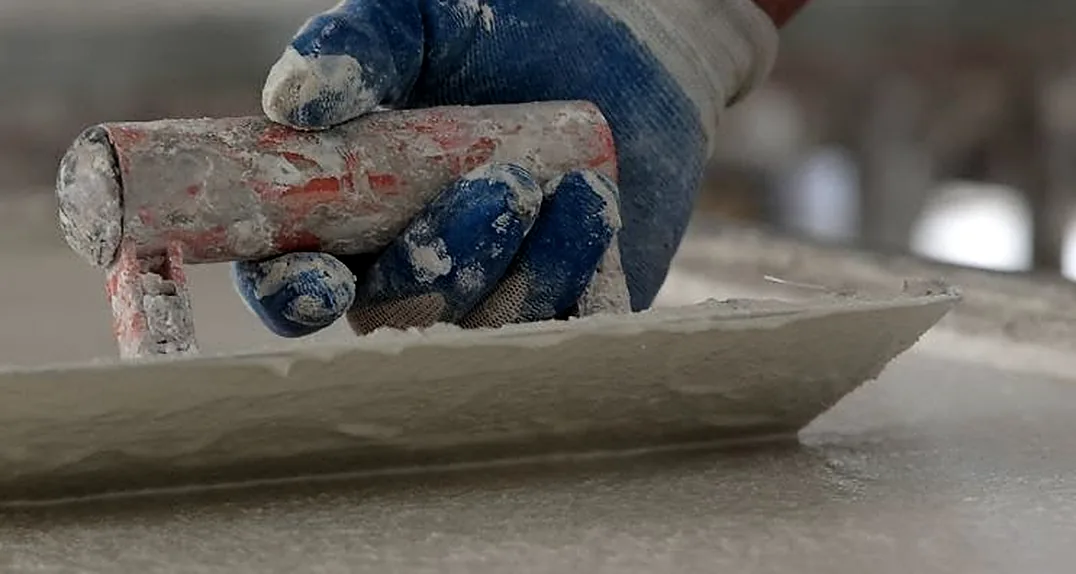 Hand-finishing a concrete surface with a trowel at the Q-Furniture factory